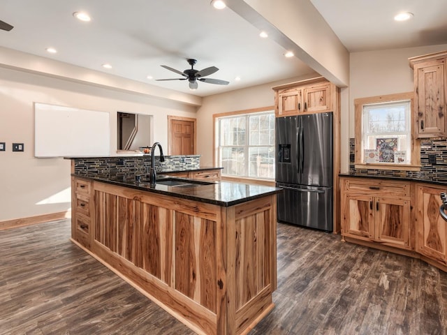 kitchen with stainless steel refrigerator with ice dispenser, ceiling fan, dark hardwood / wood-style flooring, sink, and dark stone countertops