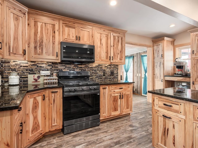 kitchen featuring decorative backsplash, dark wood-type flooring, stainless steel appliances, and dark stone counters