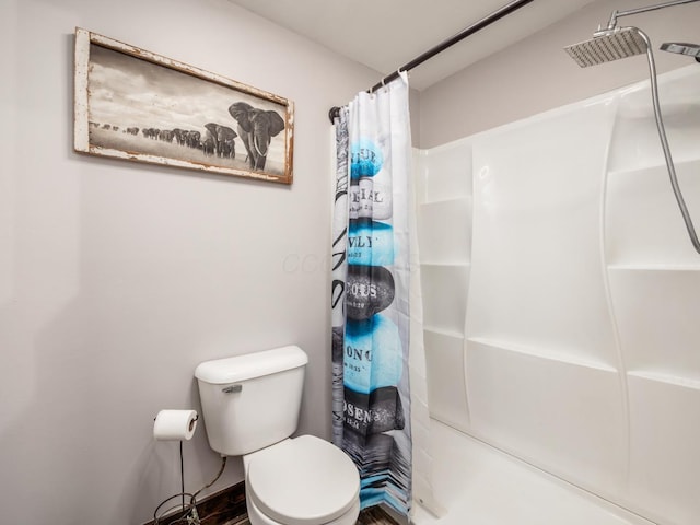 bathroom featuring toilet and curtained shower