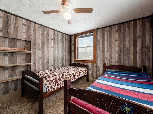 carpeted bedroom featuring wood walls, a textured ceiling, and ceiling fan