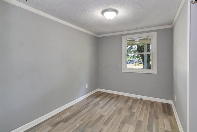 empty room with a textured ceiling, light hardwood / wood-style floors, and crown molding