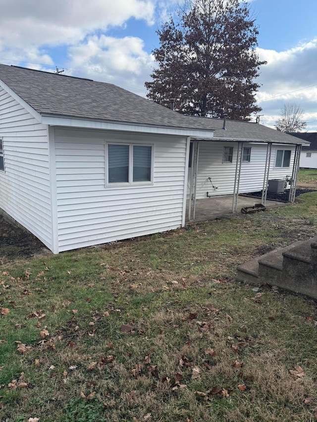 rear view of property featuring central AC unit and a lawn