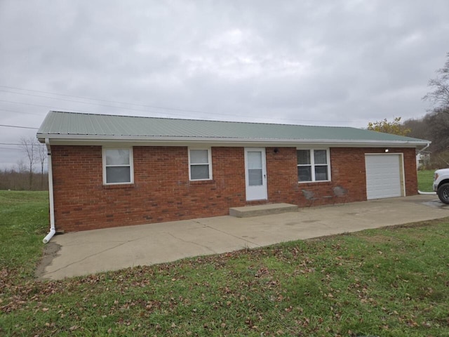 ranch-style house with a front lawn, concrete driveway, an attached garage, metal roof, and brick siding