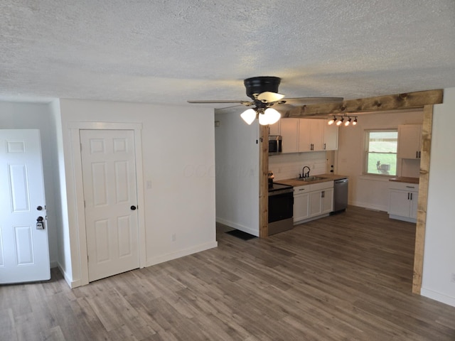 kitchen with a sink, backsplash, white cabinetry, stainless steel appliances, and dark wood-style flooring