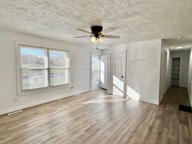 interior space featuring visible vents, baseboards, a textured ceiling, and wood finished floors