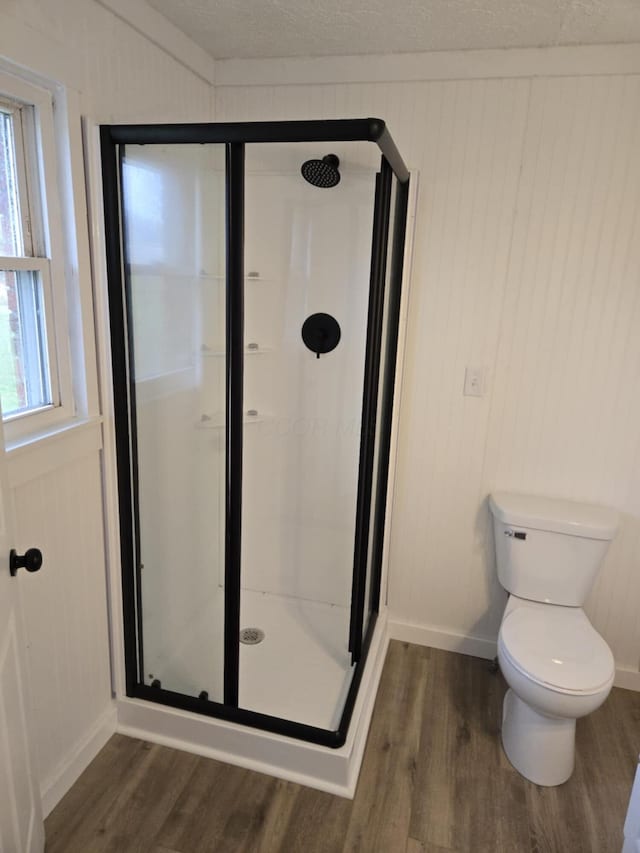 full bathroom featuring a healthy amount of sunlight, a stall shower, toilet, and wood finished floors