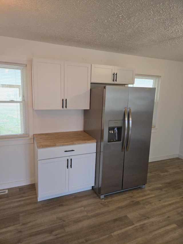 kitchen featuring dark wood-style floors, wooden counters, stainless steel fridge with ice dispenser, white cabinets, and a textured ceiling