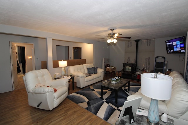 living room with hardwood / wood-style flooring, ceiling fan, and a wood stove