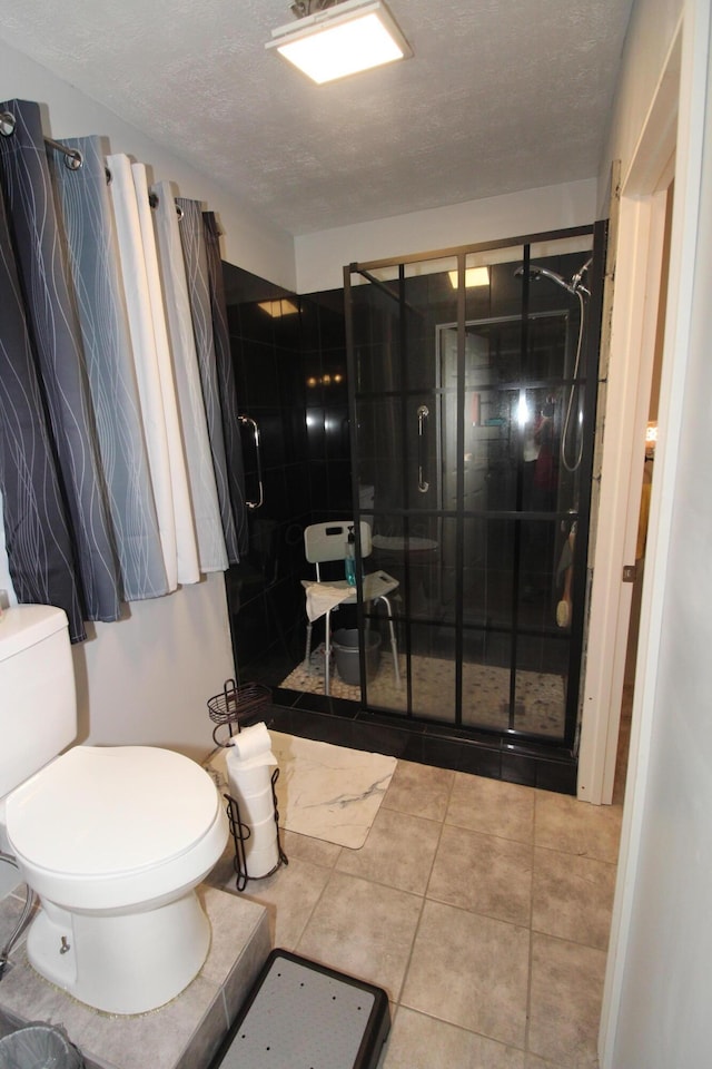 bathroom with tiled shower, a textured ceiling, and toilet