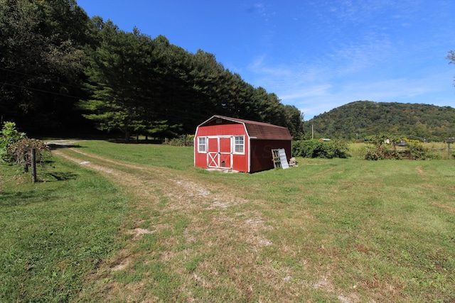 view of outdoor structure with a mountain view, a rural view, and a lawn