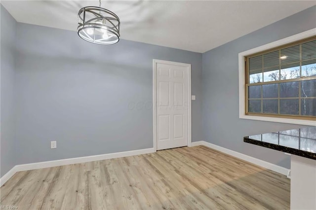 unfurnished dining area featuring light hardwood / wood-style floors and an inviting chandelier