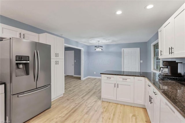 kitchen featuring white cabinets, stainless steel fridge, and dark stone counters