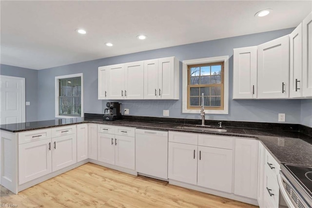 kitchen featuring white cabinetry, sink, white dishwasher, dark stone counters, and light hardwood / wood-style floors