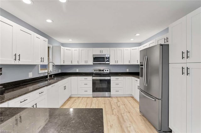 kitchen with dark stone counters, sink, white cabinets, and stainless steel appliances