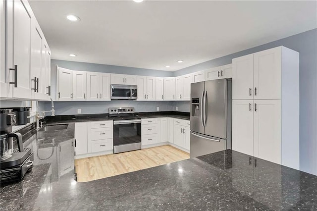 kitchen with dark stone countertops, white cabinetry, sink, and stainless steel appliances