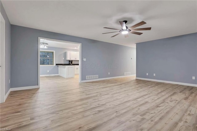 unfurnished living room with ceiling fan with notable chandelier and light wood-type flooring