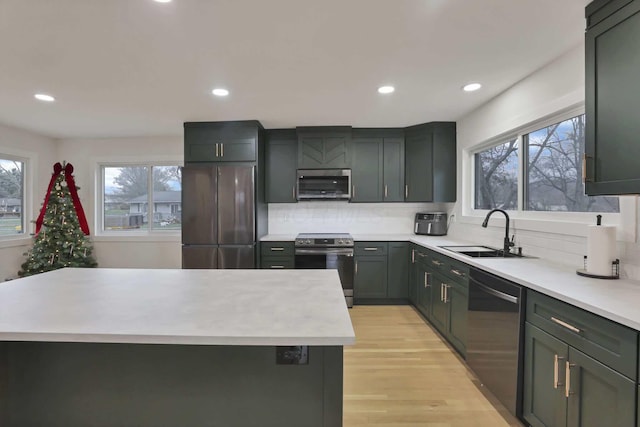 kitchen featuring sink, decorative backsplash, a kitchen island, light hardwood / wood-style floors, and stainless steel appliances