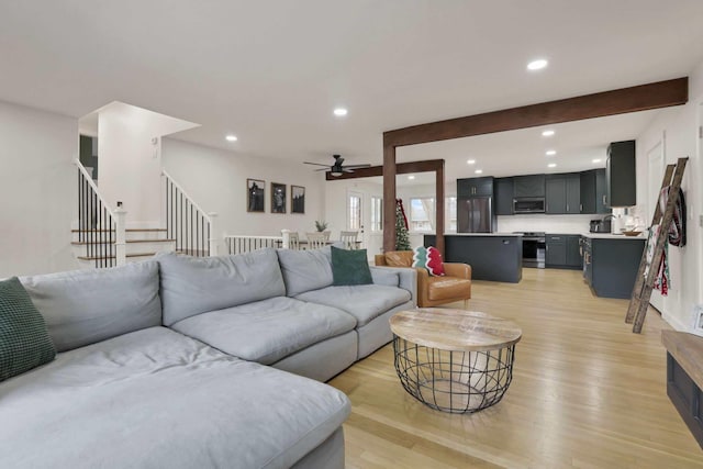 living room featuring beamed ceiling, light hardwood / wood-style flooring, and ceiling fan