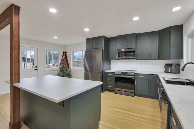 kitchen featuring decorative backsplash, appliances with stainless steel finishes, light wood-type flooring, sink, and a center island