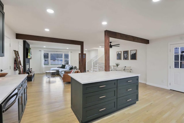 kitchen with beam ceiling, a center island, stainless steel dishwasher, and light hardwood / wood-style flooring