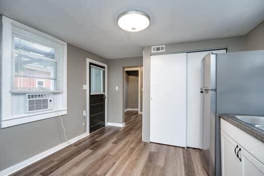 kitchen with white cabinets, stainless steel fridge, wood-type flooring, and cooling unit