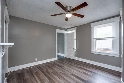 unfurnished living room with ceiling fan and dark wood-type flooring