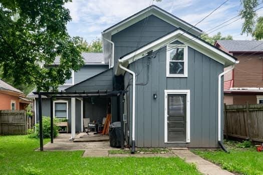 back of property featuring a pergola, an outdoor structure, and a lawn