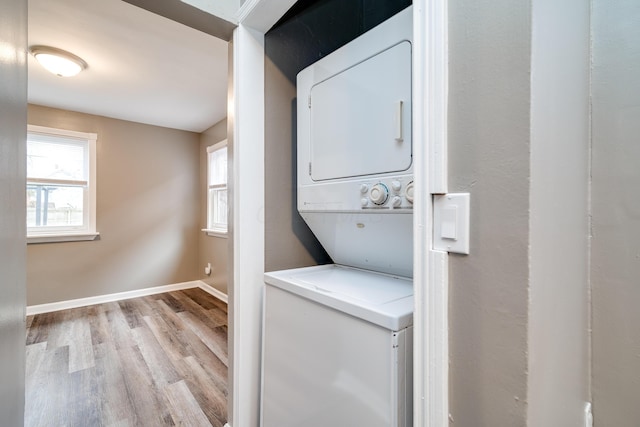 laundry room featuring a wealth of natural light, light hardwood / wood-style flooring, and stacked washing maching and dryer