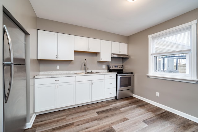 kitchen featuring stainless steel appliances, white cabinetry, light hardwood / wood-style floors, and sink