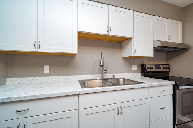 kitchen with electric range, sink, white cabinets, and light stone counters