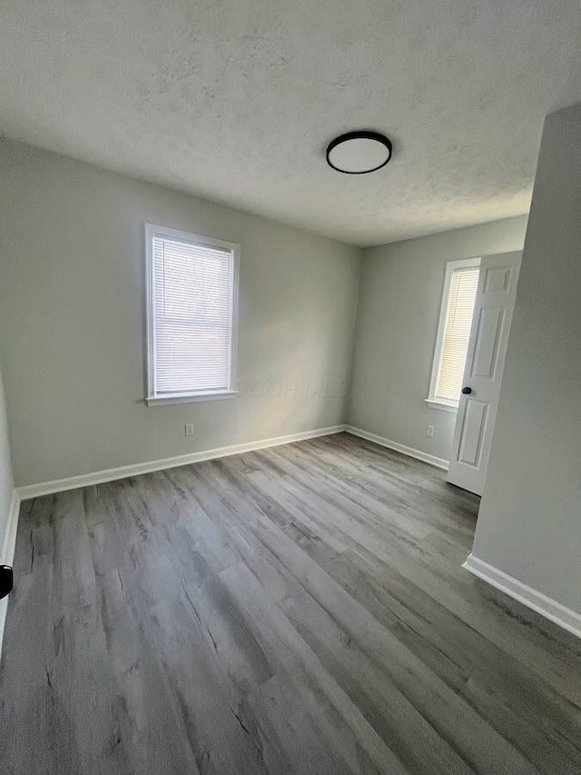 unfurnished room featuring light hardwood / wood-style floors and a textured ceiling