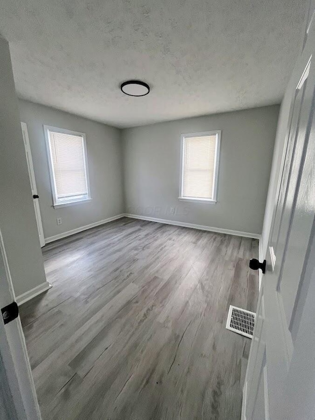 spare room featuring hardwood / wood-style floors and a textured ceiling