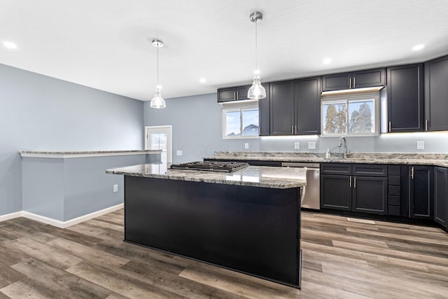 kitchen with pendant lighting, a center island, light stone counters, and stainless steel appliances