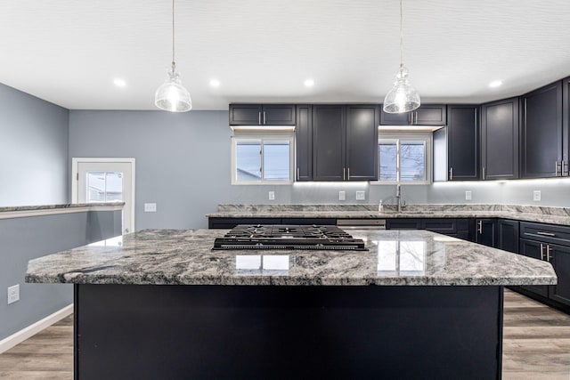 kitchen featuring pendant lighting, plenty of natural light, a kitchen island, and light stone countertops