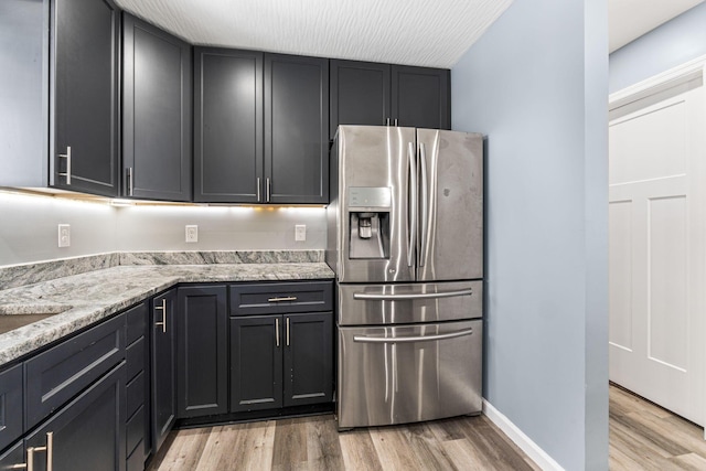 kitchen featuring stainless steel fridge, light stone countertops, and light hardwood / wood-style floors