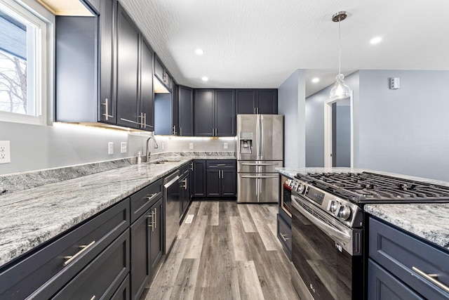 kitchen featuring light stone countertops, sink, hanging light fixtures, and appliances with stainless steel finishes