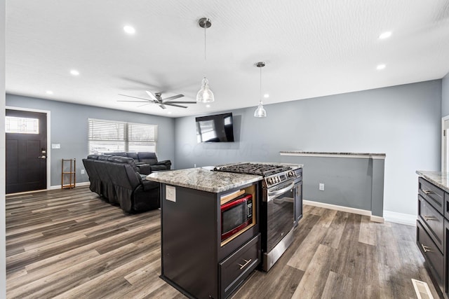 kitchen featuring a center island, light stone countertops, stainless steel range with gas cooktop, and hanging light fixtures