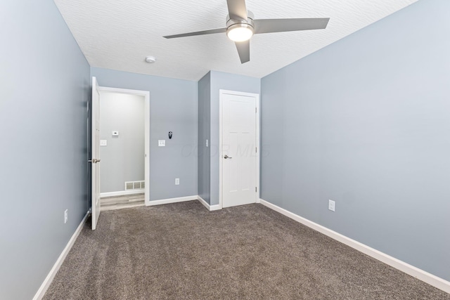 unfurnished bedroom with ceiling fan, a textured ceiling, and dark colored carpet