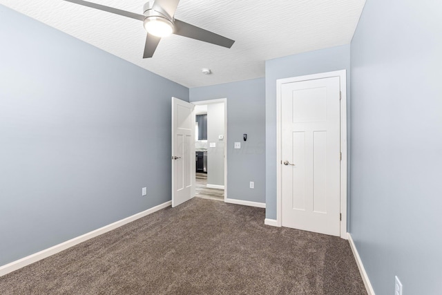 unfurnished bedroom featuring dark colored carpet, a textured ceiling, and ceiling fan