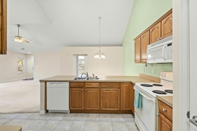 kitchen with white appliances, kitchen peninsula, sink, and hanging light fixtures