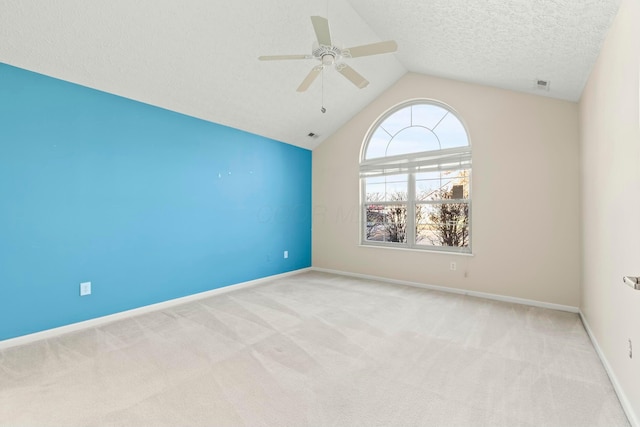 spare room with ceiling fan, lofted ceiling, light carpet, and a textured ceiling