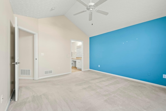 unfurnished bedroom featuring ensuite bathroom, light colored carpet, high vaulted ceiling, a textured ceiling, and ceiling fan