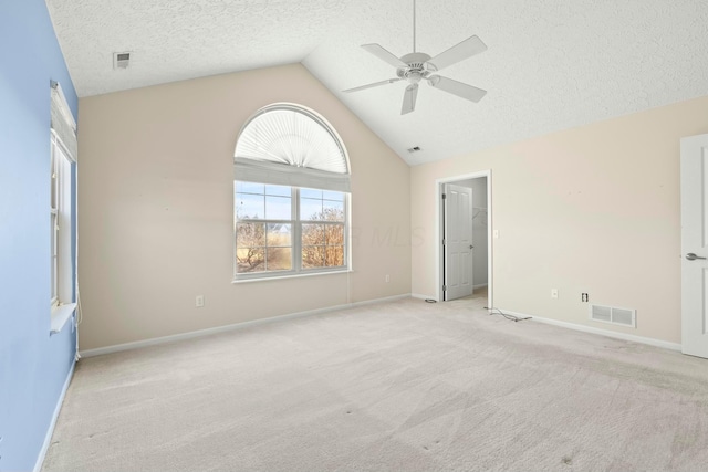 carpeted empty room featuring ceiling fan, lofted ceiling, and a textured ceiling