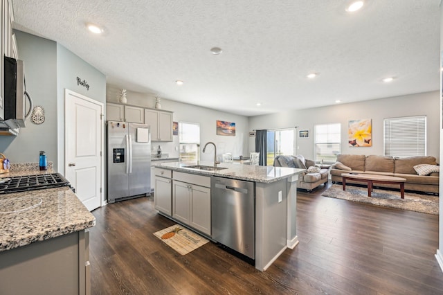 kitchen with gray cabinets, a center island with sink, stainless steel appliances, and sink