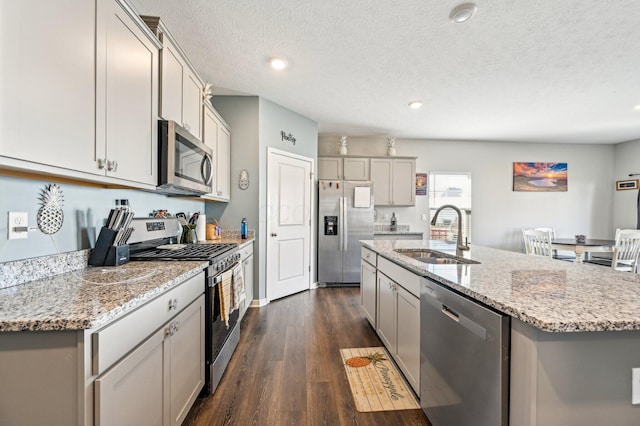 kitchen with sink, dark wood-type flooring, stainless steel appliances, an island with sink, and a textured ceiling