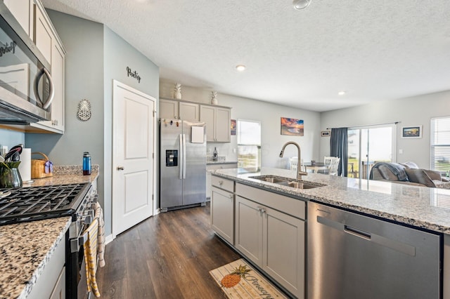 kitchen featuring dark wood-type flooring, sink, gray cabinets, light stone counters, and stainless steel appliances