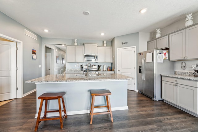 kitchen with sink, an island with sink, and stainless steel appliances