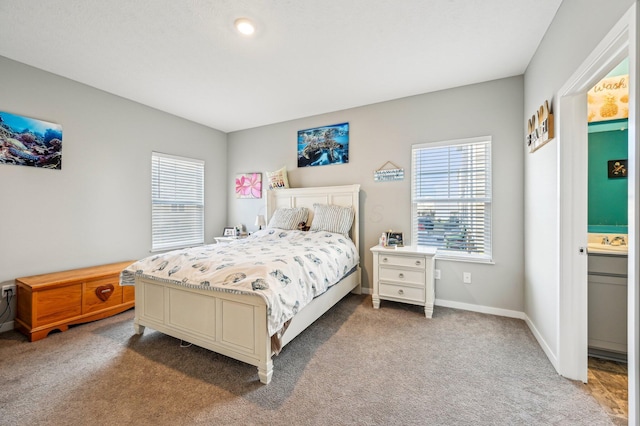 carpeted bedroom with sink and ensuite bath