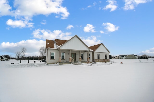 snow covered rear of property with covered porch