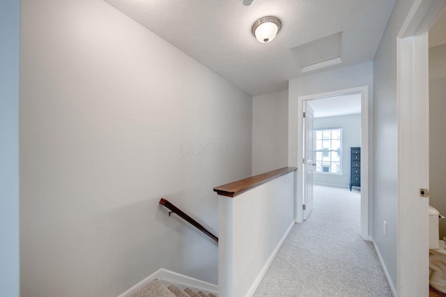 corridor with a textured ceiling and light colored carpet